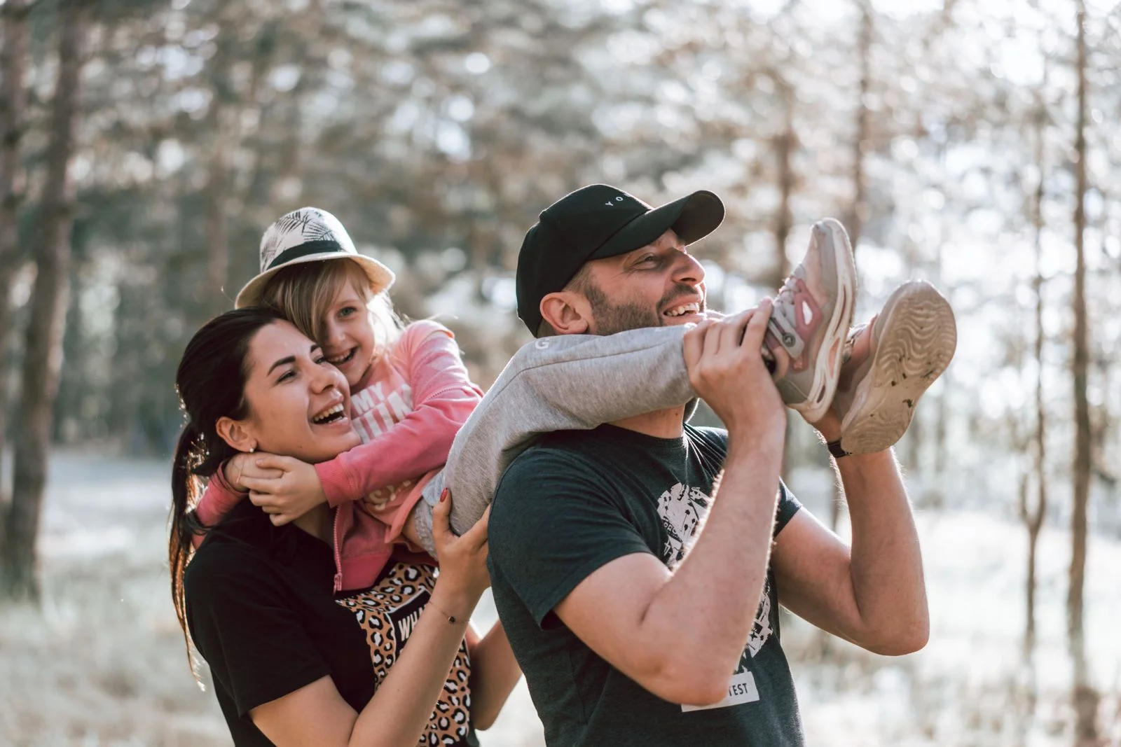 Un père porte sa fille sur les épaules, la mère rit à côté d’eux