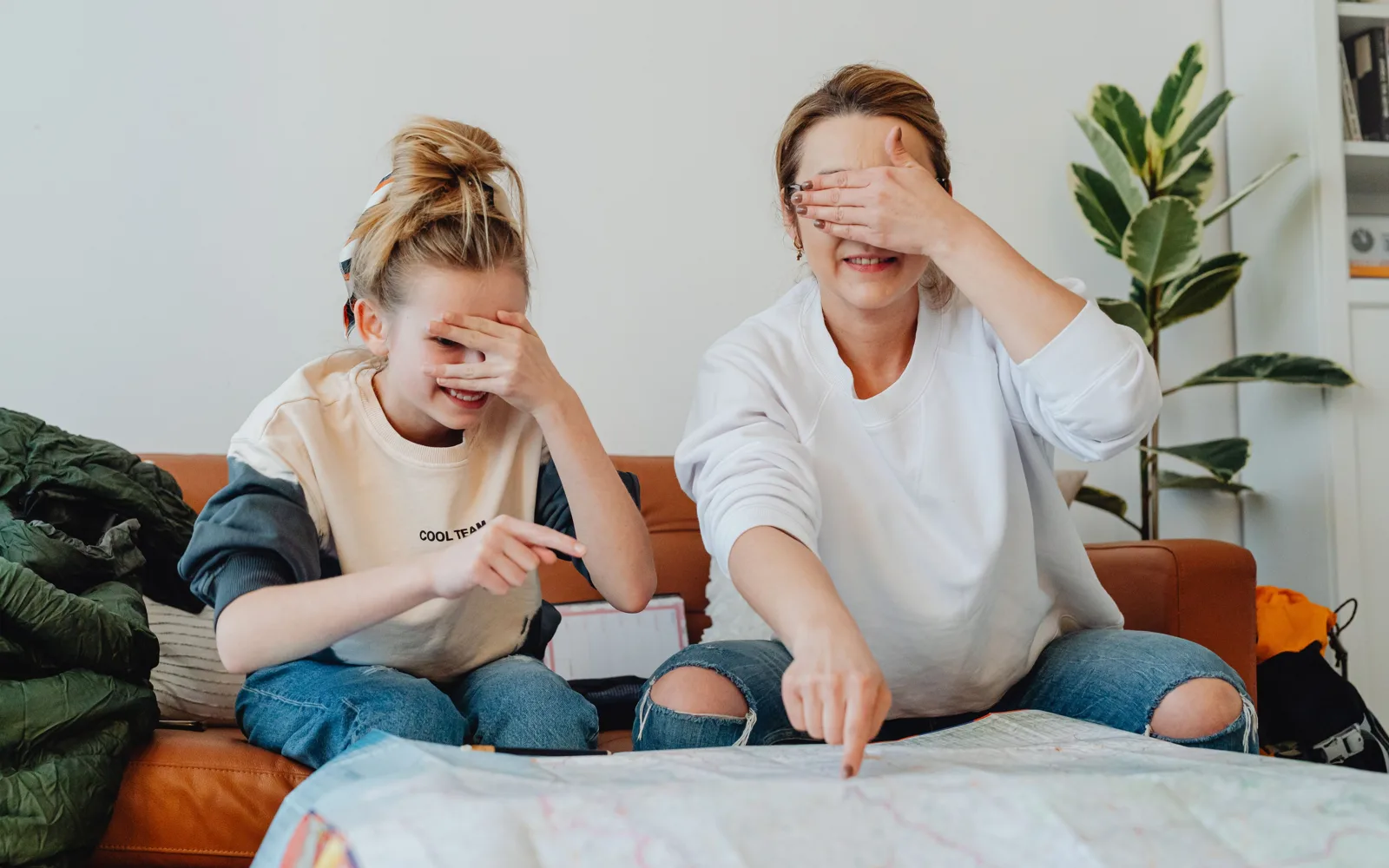 Une mère, les yeux cachés, et sa fille pointent au hasard une carte dépliée pour choisir leur sortie