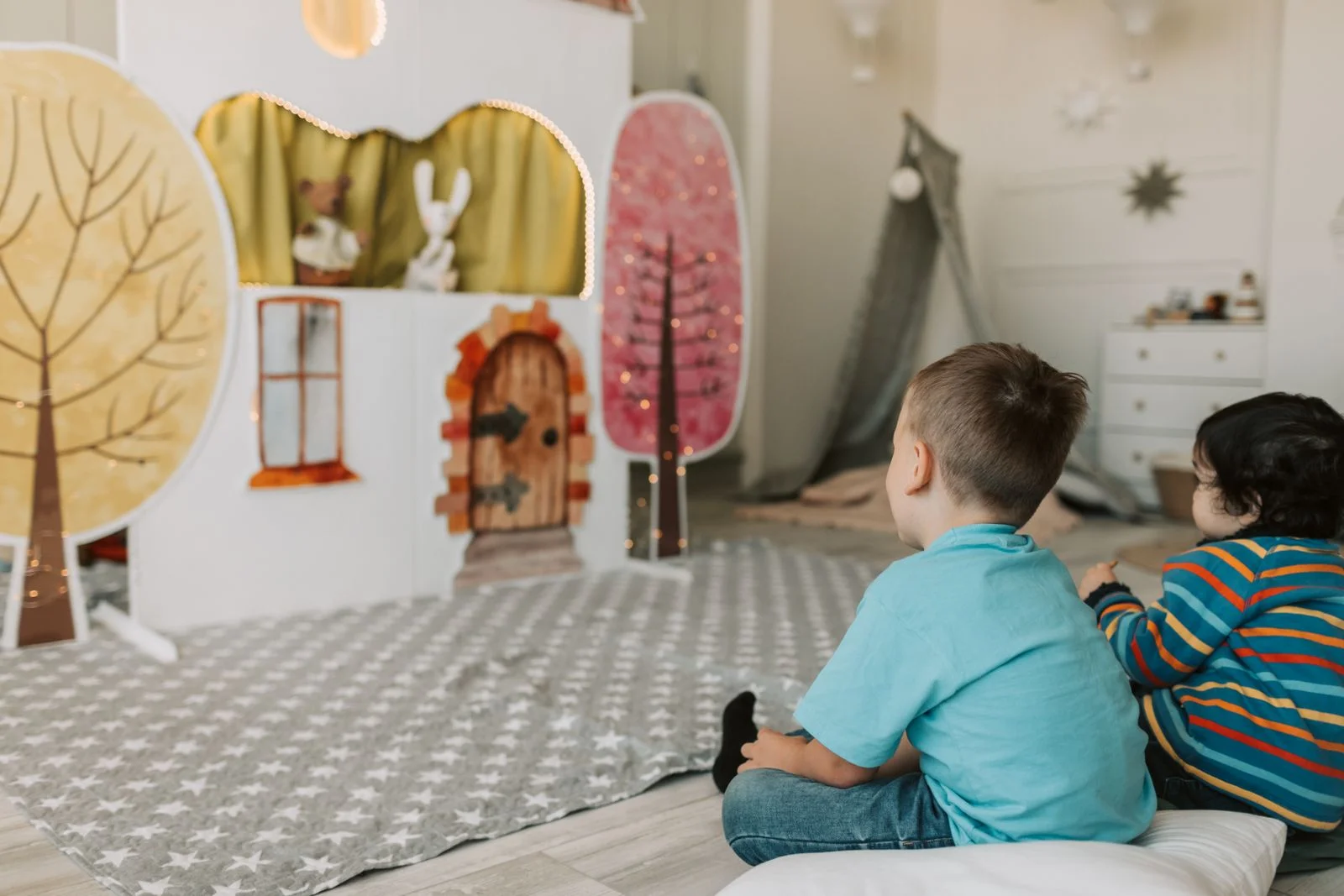 Deux enfants assis par terre regardent un spectacle de marionnettes